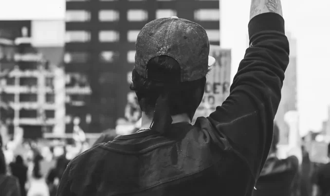 Man in a crowd, raising a fist in solidarity